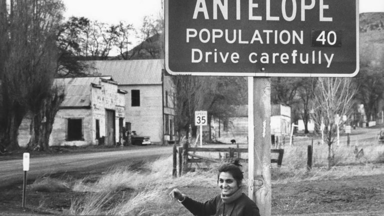 Sheela posa na frente da placa de Antelope, a comunidade norte-americana que se revoltou contra a construção de Rajneeshpuram