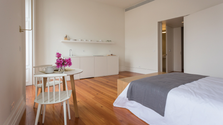 Uma mesa, uma cama e uma cozinha podem conviver no mesmo espaço, sem lhe retirar o bom ar