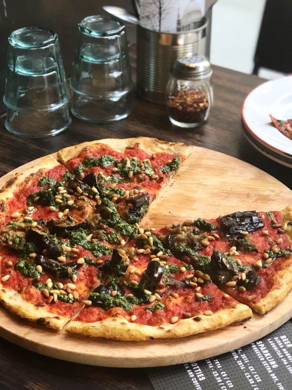 A pizza de beringela, tomate, pinhões, e pesto 
